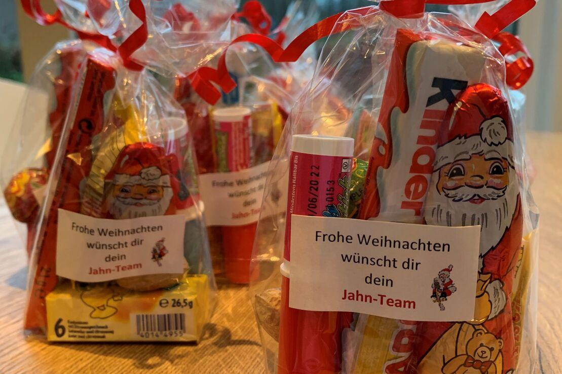 T&uuml;ten mit Weihnachtsgeschenken, verpackt in Folie, mit Etiketten, die festliche Gr&uuml;&szlig;e vom Jahn-Team enthalten.