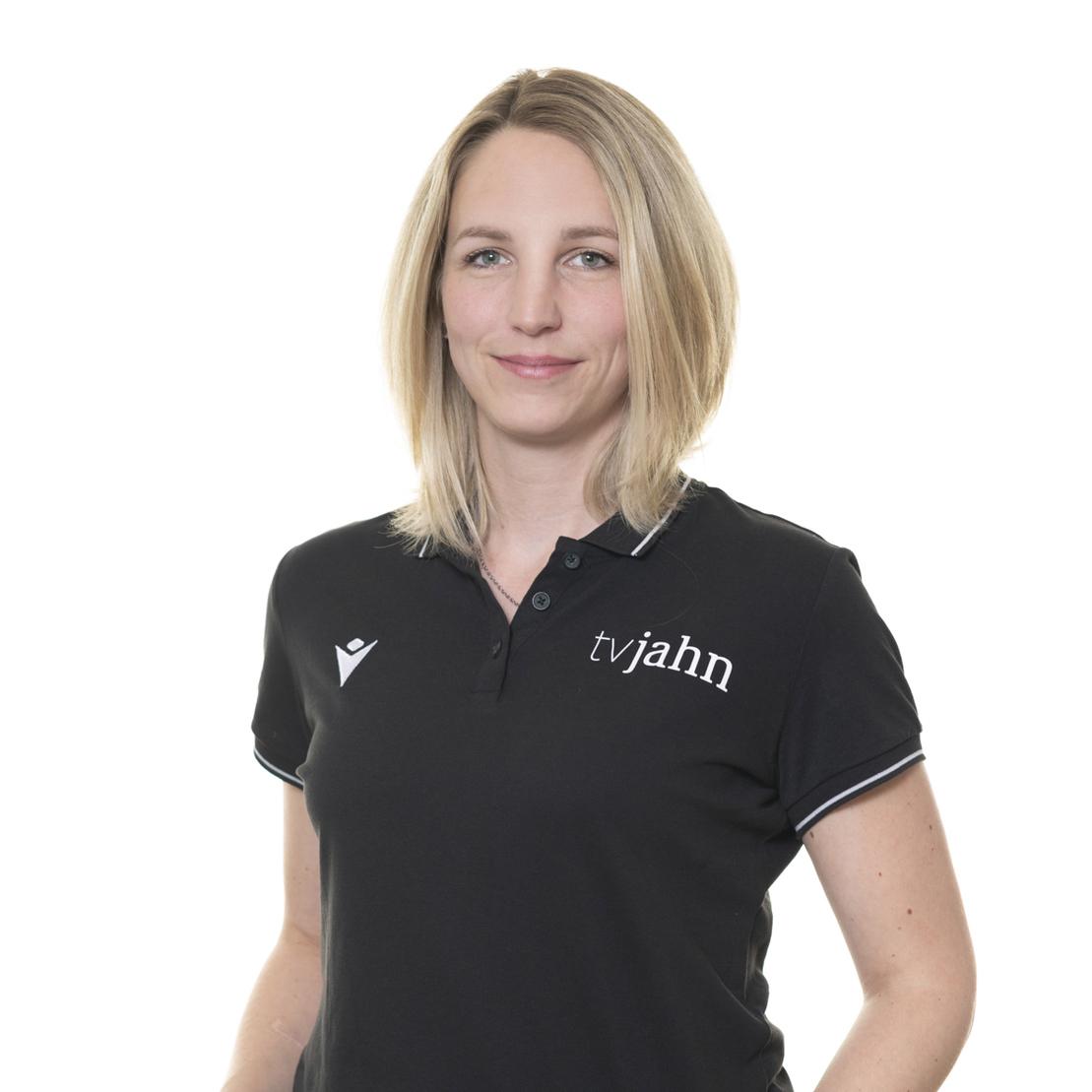 Portr&auml;t einer Frau mit kurzer blonder Haarfrisur, die ein schwarzes Polo-Shirt mit dem Logo "tvjahn" tr&auml;gt.