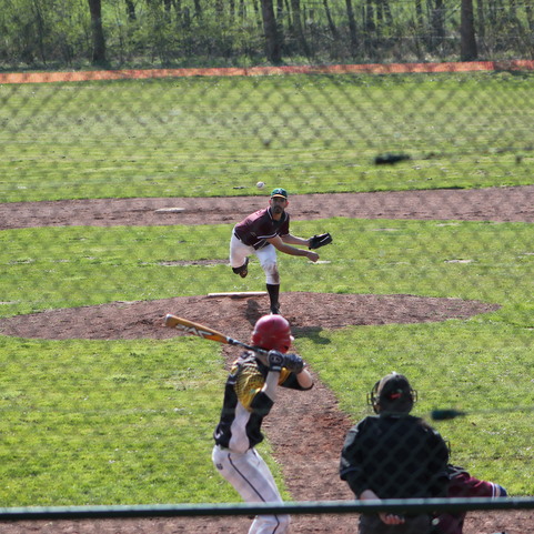 Baseballspiel im Freien: Pitcher wirft den Ball zu einem Schlagmann, w&auml;hrend der Schiedsrichter in der unteren Ecke beobachtet.