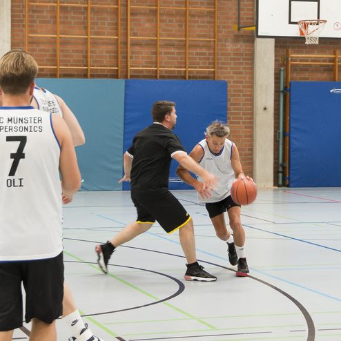 Basketballspiel mit zwei Spielern; einer dribbelt den Ball, der andere versucht, ihn zu verteidigen.