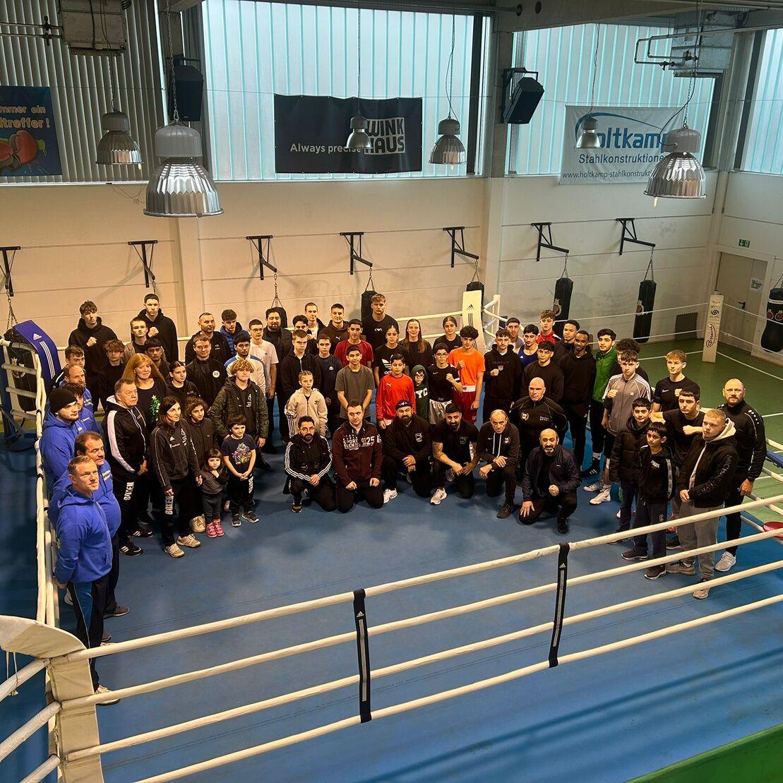 Gruppennfoto von über 60 Personen in Sportkleidung im Boxring eines Trainingszentrums.