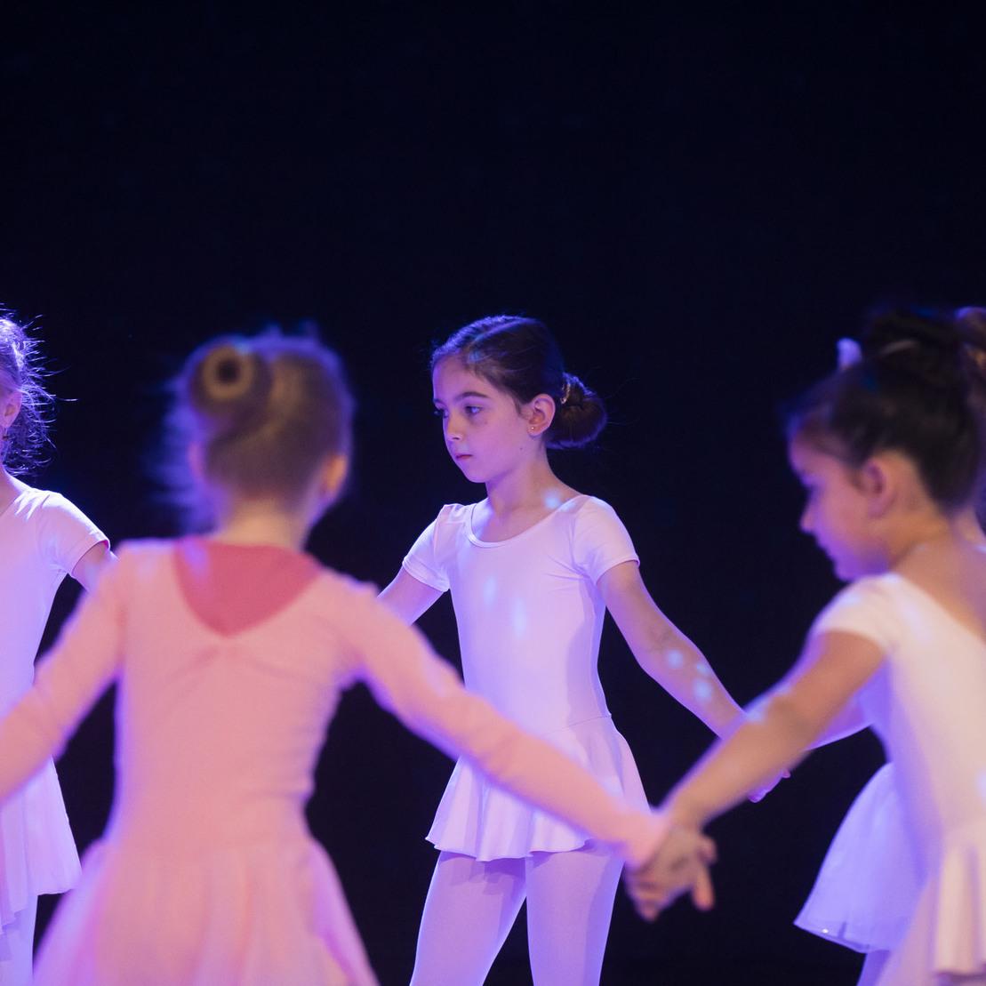 F&uuml;nf kleine Ballettt&auml;nzerinnen in rosa und wei&szlig;en Kost&uuml;men stehen im Kreis und halten sich an den H&auml;nden.