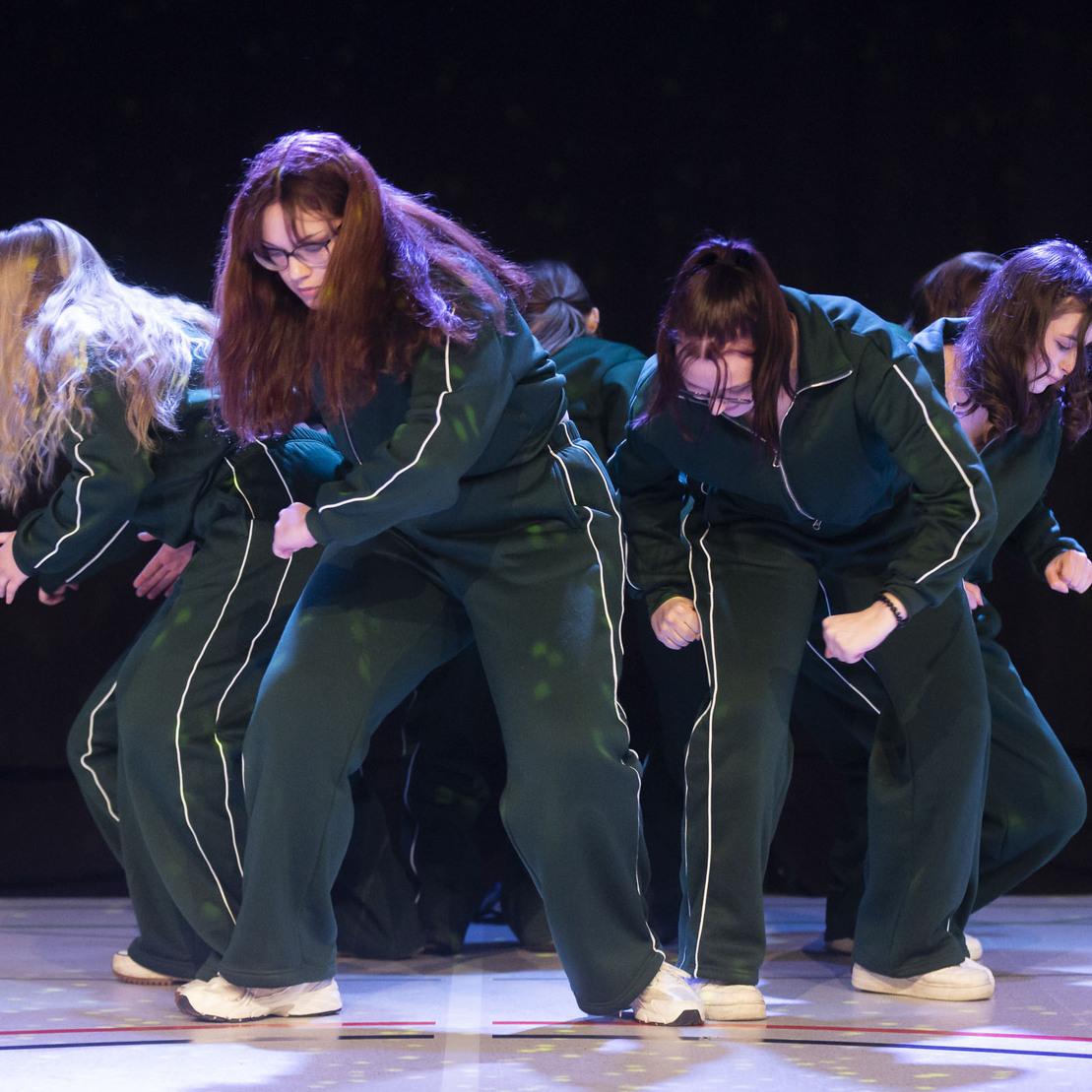 F&uuml;nf T&auml;nzerinnen in sportlichen Outfits f&uuml;hren synchron eine choreografierte Tanzroutine auf.