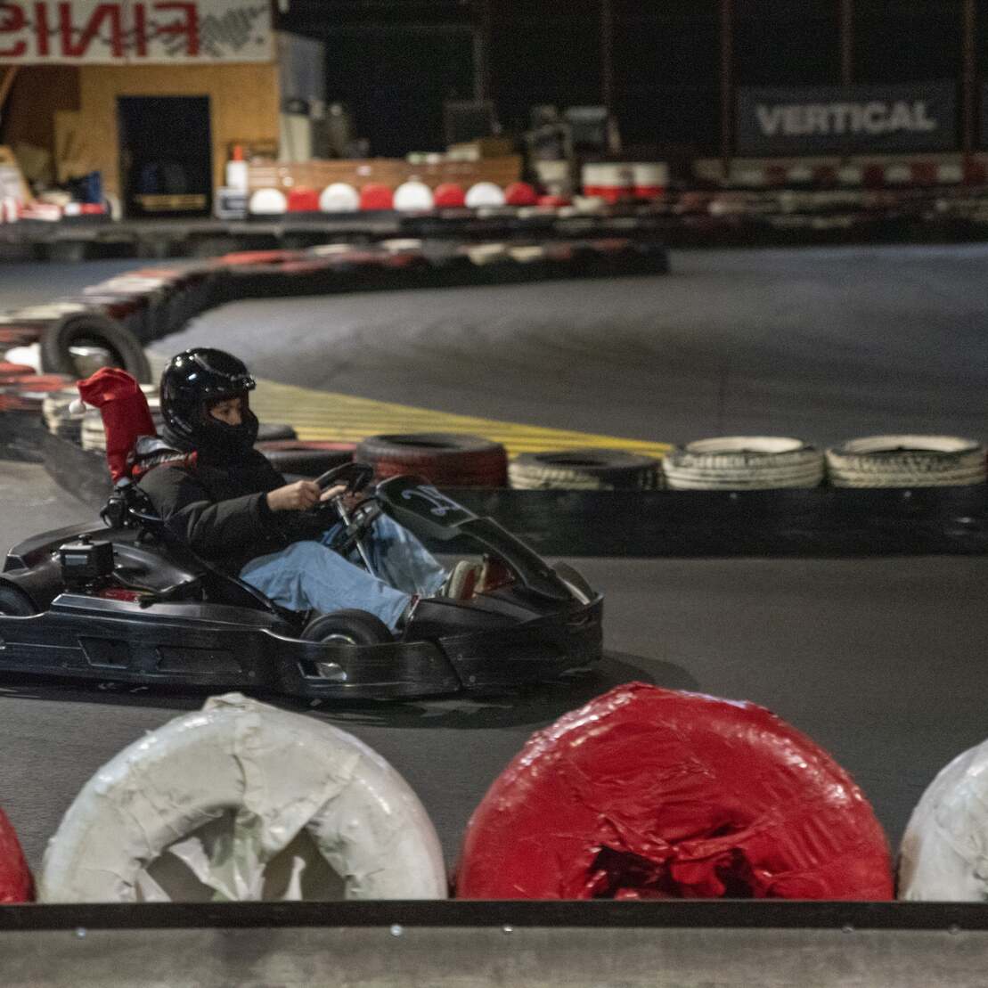 Fahrer in einem Go-Kart auf einer Rennstrecke mit roten und wei&szlig;en Reifen als Abgrenzung.