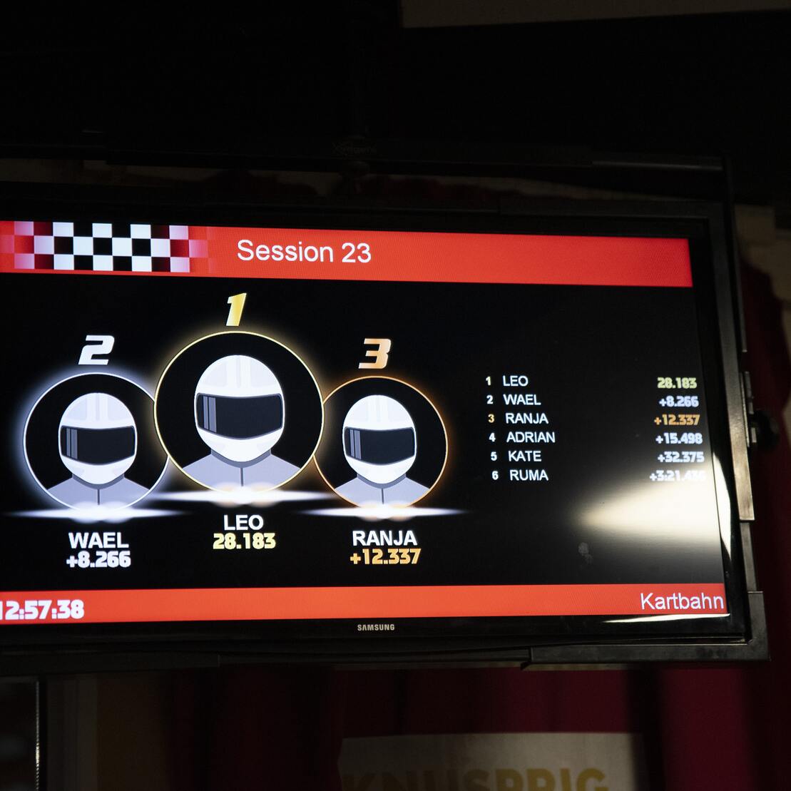 Anzeigetafel mit Ranglisten der Kartbahn: Leo f&uuml;hrt, gefolgt von Wael und Ranja, mit entsprechenden Zeitangaben.