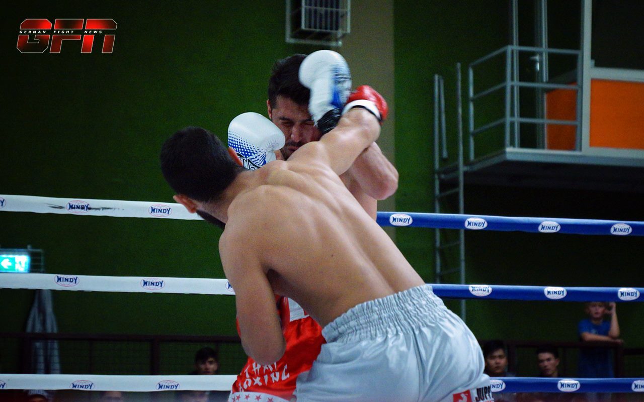 Zwei Boxer im Ring, einer trifft den Gegner mit einem Schlag, beide tragen Schutzausr&uuml;stung und Sportkleidung.