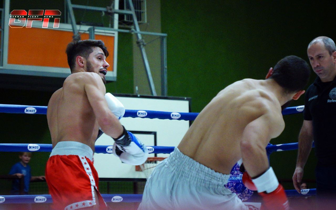 Zwei Boxer im Ring w&auml;hrend eines Wettkampfs, der eine f&uuml;hrt einen Rechtssto&szlig; aus, Schiedsrichter beobachtet.