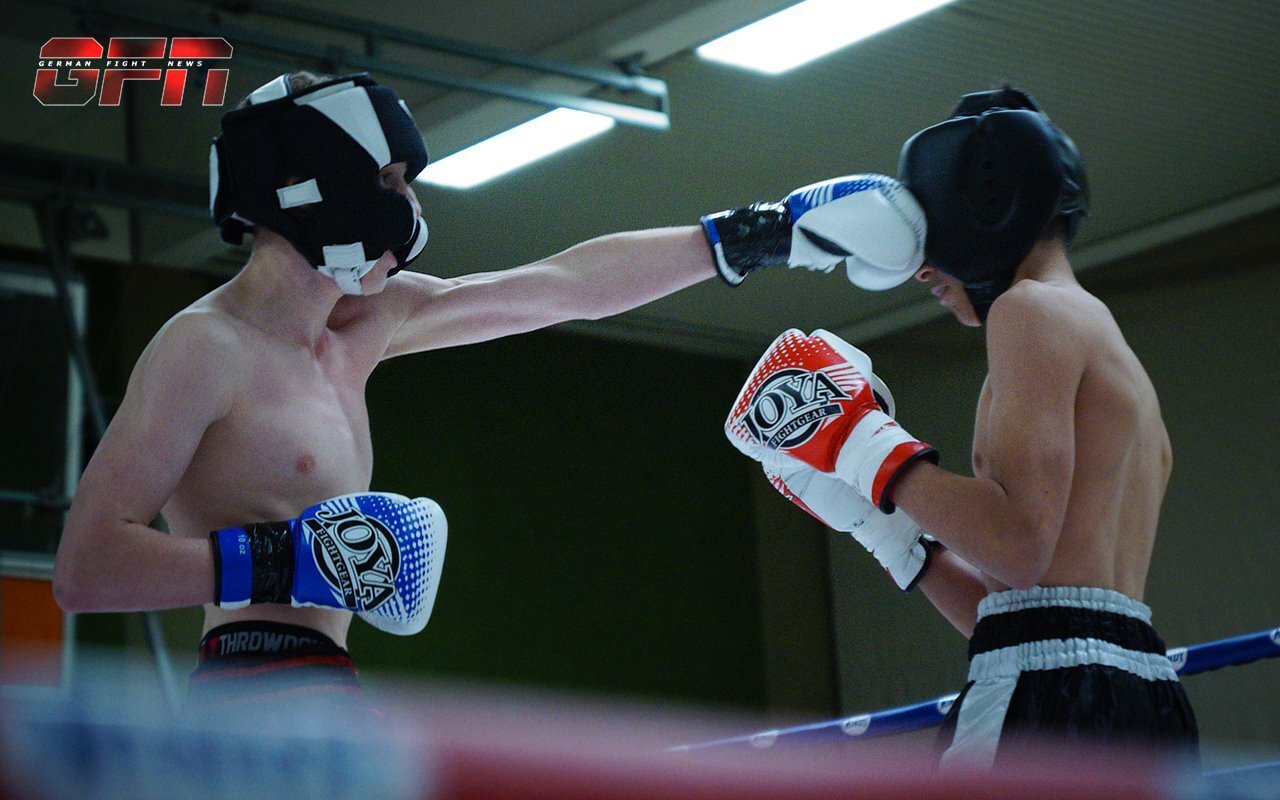 Zwei Boxer im Ring, einer f&uuml;hrt einen Jab aus, beide tragen Handschuhe und Schutzmasken.