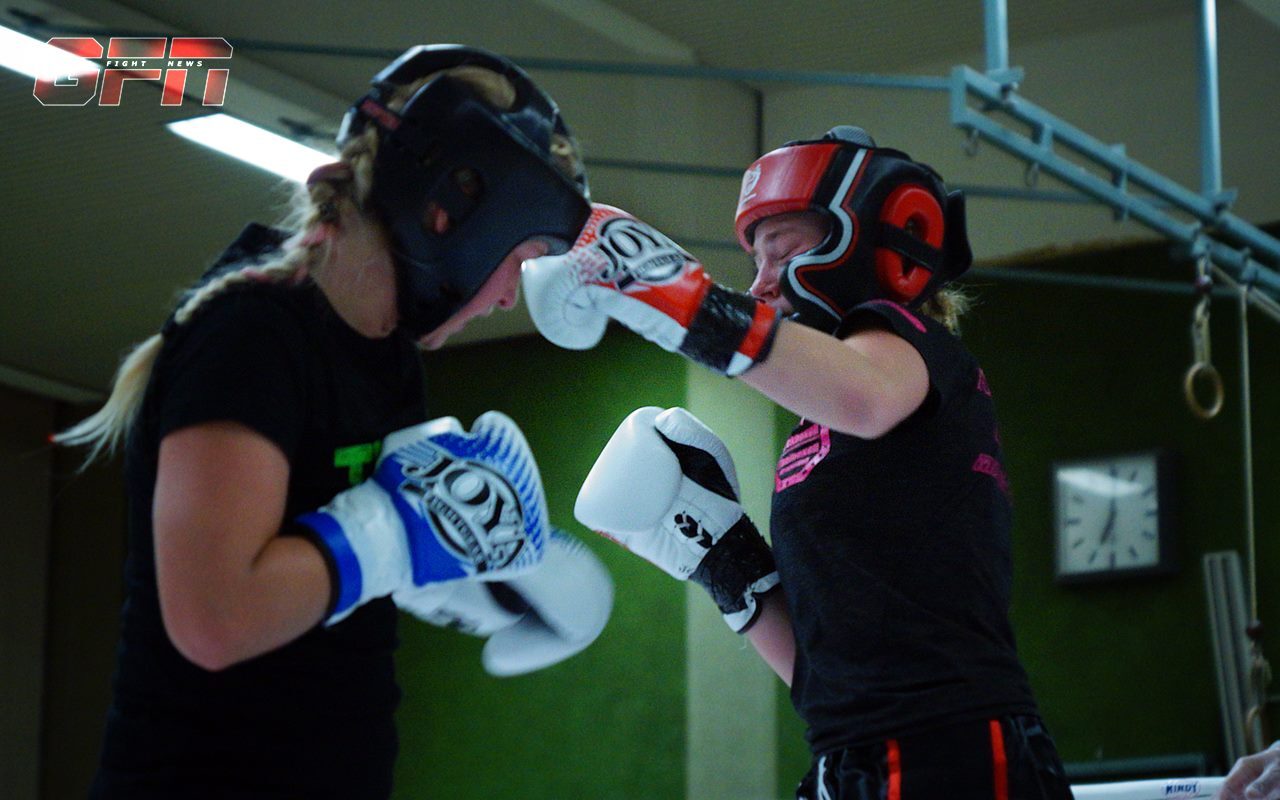 Zwei weibliche Boxerinnen in Schutzhelmen und Boxhandschuhen in einem Sparring auf einem Boxring.