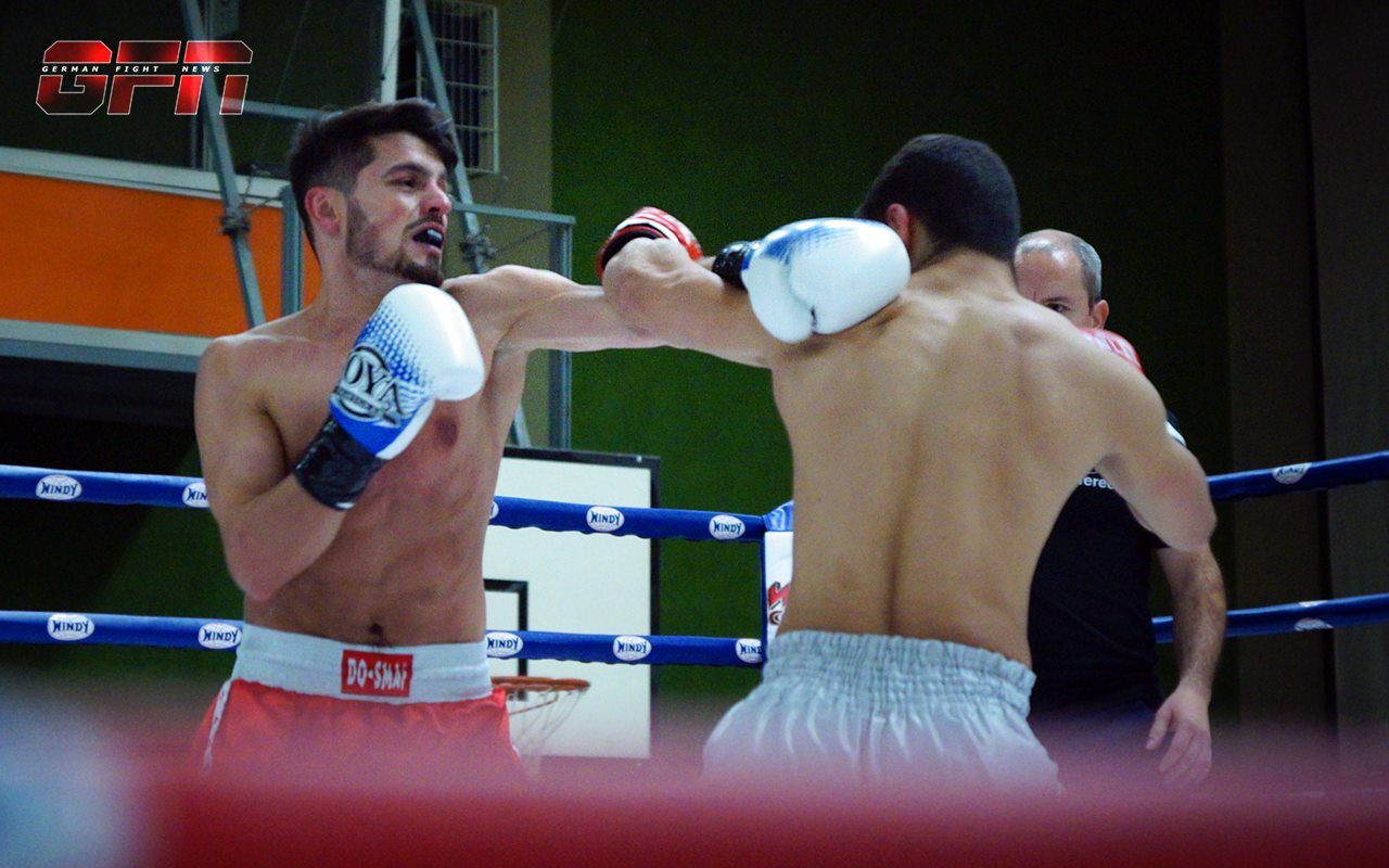 Zwei m&auml;nnliche Boxer im Ring, der linke trifft mit einem rechten Haken den Gegner, der sich verteidigt.