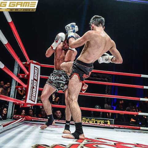 Zwei K&auml;mpfer im Ring f&uuml;hren einen Schlagabtausch aus, einer tritt, w&auml;hrend der andere einen Defensive h&auml;lt.