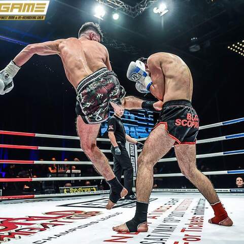 Zwei K&auml;mpfer in einem Boxring f&uuml;hren einen Schlagwechsel aus; Hervorhebung des dynamischen Moments.