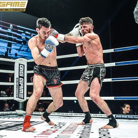 Zwei K&auml;mpfer im Ring w&auml;hrend eines Kampfes, einer weicht einem Schlag aus und tr&auml;gt Sporthandschuhe.