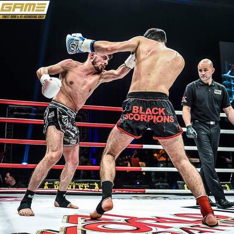 Zwei K&auml;mpfer im Ring w&auml;hrend eines Kickbox-Matches, einer schl&auml;gt mit einem rechten Haken, der andere weicht aus.