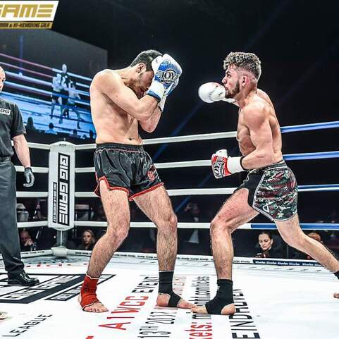 Zwei K&auml;mpfer im Boxring w&auml;hrend eines Matches, Schiedsrichter beobachtet die Situation.