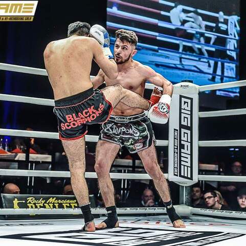 Zwei K&auml;mpfer in einem Ring, einer f&uuml;hrt einen Kniesto&szlig; aus, w&auml;hrend der andere in der Abwehrposition ist.