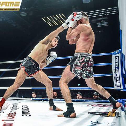 Zwei K&auml;mpfer im Ring w&auml;hrend eines Wettkampfs, einer schl&auml;gt mit einem rechten Haken, der andere blockt.