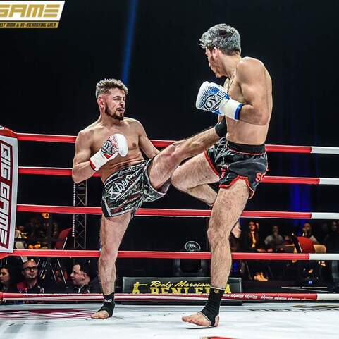 Zwei K&auml;mpfer im Ring, einer tritt mit dem Knie gegen den anderen w&auml;hrend eines Muay Thai-Matches.