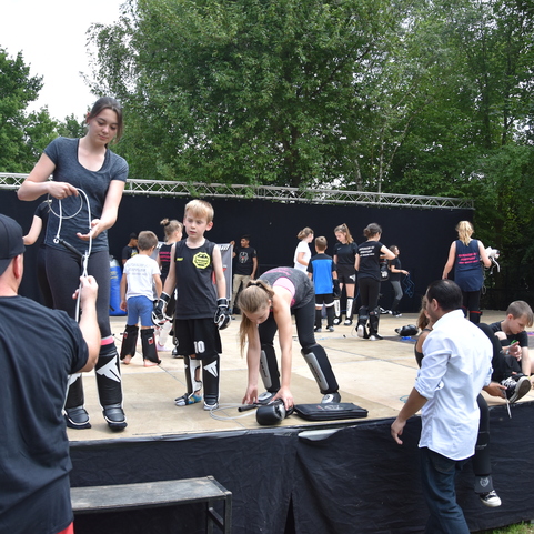 Gruppentraining auf einer Freiluftb&uuml;hne mit Kindern und Erwachsenen in Sportkleidung, die Ausr&uuml;stung vorbereiten.