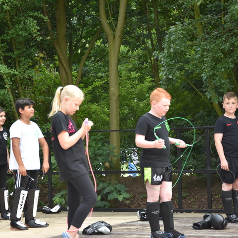 Sechs Kinder in Sportkleidung stehen im Freien und halten Seile in der Hand, um zu springen.