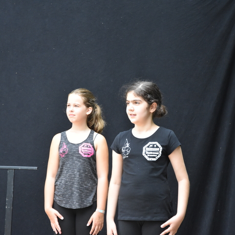 Zwei Kinder in sportlicher Kleidung stehen auf einer B&uuml;hne vor einem schwarzen Hintergrund.