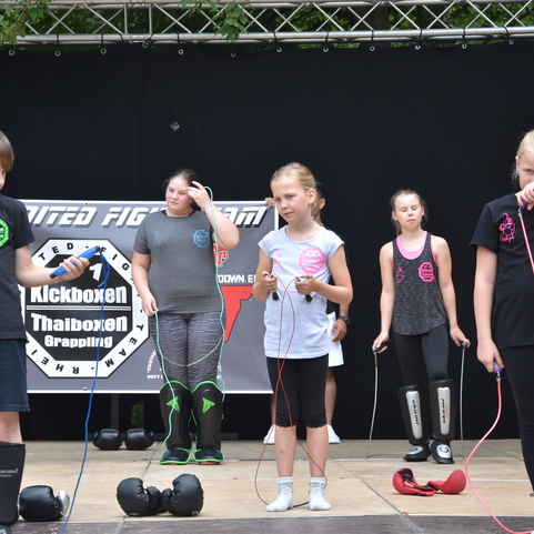 Kinder in Sportkleidung halten Springseile auf einer B&uuml;hne w&auml;hrend einer Veranstaltung zum Kampfsporttraining.