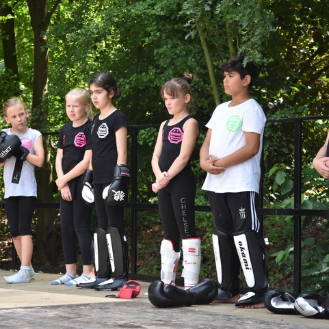 Sechs Kinder in Trainingskleidung stehen in einer Reihe, bereit f&uuml;r das Karate-Training im Freien.