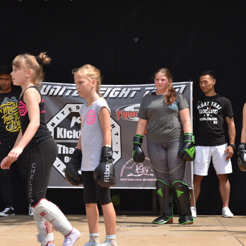 Gruppentraining mit mehreren Kindern in Sportkleidung, die Kickbox- und Thaibox-Ausr&uuml;stung tragen.
