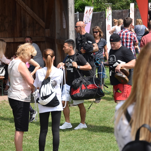 Menschenmenge auf einem festlichen Event, mit Teilnehmern, die Taschen tragen und Gespr&auml;che f&uuml;hren.