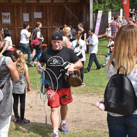 Mann in Sportkleidung tr&auml;gt zwei gro&szlig;e Wasserflaschen in einem Besucherbereich eines Festes. Menschenmengen im Hintergrund.