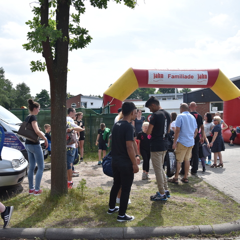 Menschen stehen unter einem gro&szlig;en bunten Tor mit dem Schriftzug &bdquo;Familienfest&ldquo; vor einem Veranstaltungsort.