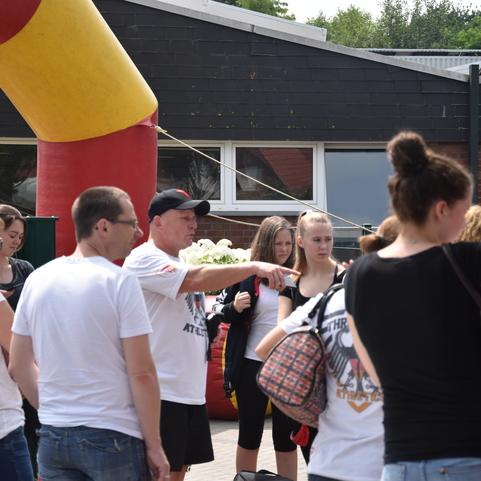 Gruppierung von Menschen im Freien, ein Mann zeigt mit dem Finger auf etwas, im Hintergrund eine Aufblaskonstruktion.