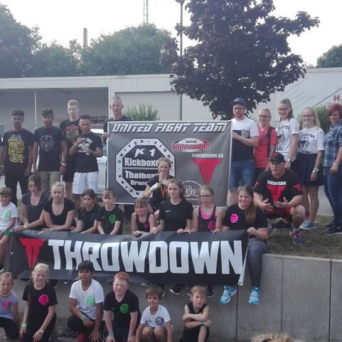 Gruppe von Jugendlichen und Erwachsenen in Sportkleidung, posierend vor einem Banner des United Fight Teams.