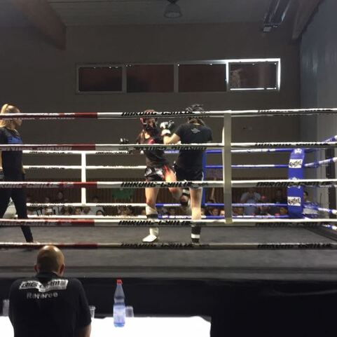 Zwei Boxer im Ring w&auml;hrend eines Wettkampfs, beobachtet von einem Publikum und einem Kamerateam.