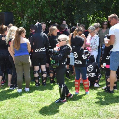 Gruppenszene mit vielen Menschen, teils in Sportkleidung, die an einer Veranstaltung im Freien teilnehmen.