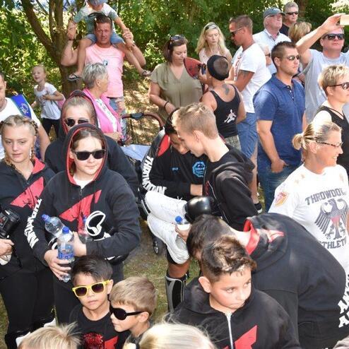 Gruppe von Menschen in Sportjacken versammelt sich bei einem Event im Freien, darunter Kinder und Erwachsene.