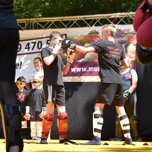 Zwei Jugendliche im Karate-Training stehen sich gegen&uuml;ber, um Techniken auf einer gelben Matte zu &uuml;ben.