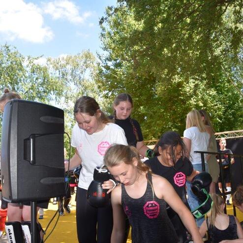 Gruppen von Jugendlichen in Sportkleidung bereiten sich im Freien mit Schutzausr&uuml;stung auf ein Training vor.