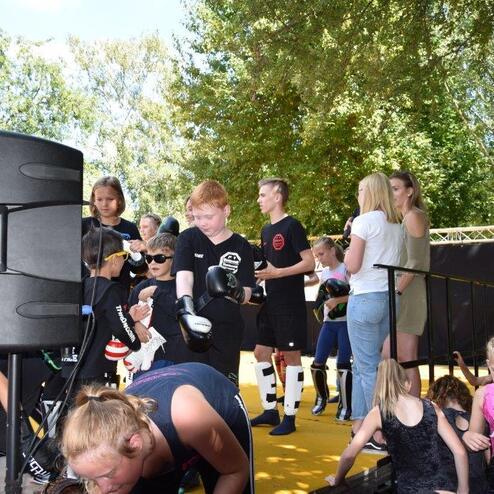 Gruppierung von Kindern und Jugendlichen auf einer Outdoor-Veranstaltung, fr&ouml;hliche Stimmung mit Sportequipment.