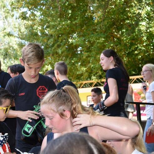 Gruppe von Kindern und Jugendlichen bei einer Veranstaltung, einige mit Sonnenbrillen, andere mit Ausr&uuml;stung in der Hand.