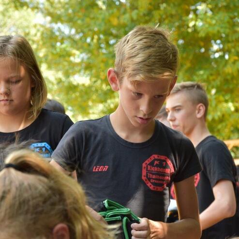 Gruppe von Kindern in schwarzen T-Shirts, die sich auf einer Veranstaltung mit konzentrierten Blicken vorbereiten.