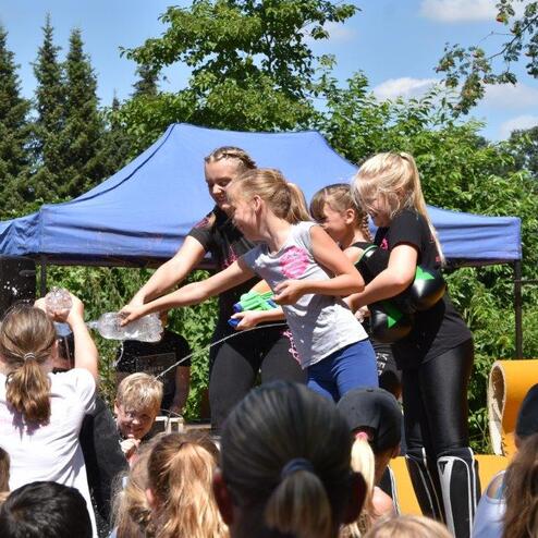 Gruppenspiel mit Kindern und Betreuern, die aktiv Schaum auf einer Outdoor-Veranstaltung verteilen.