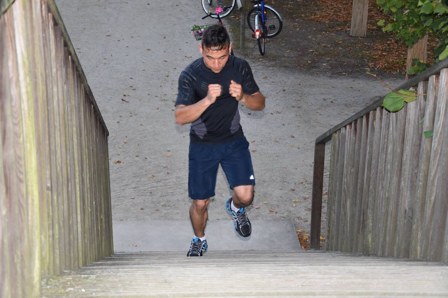 Mann in Sportkleidung joggt Treppen hinauf, im Hintergrund sind Fahrr&auml;der und ein Weg sichtbar.