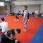 Trainingseinheit in einer Kampfsportschule mit mehreren Teilnehmern auf einer roten Matte.