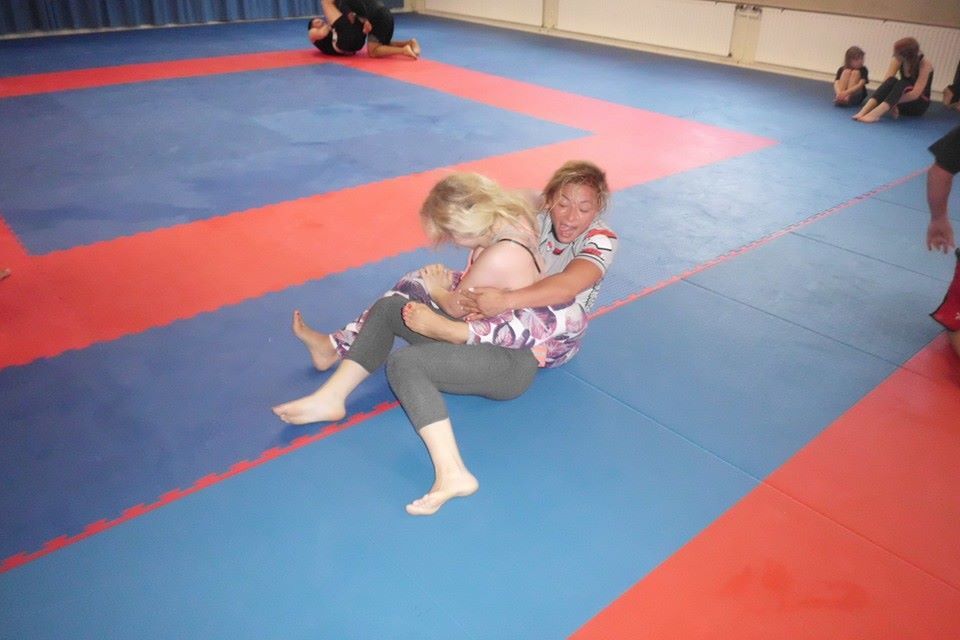 Zwei Frauen in Sportbekleidung k&auml;mpfen auf einer blauen und roten Mattenfl&auml;che im Training.