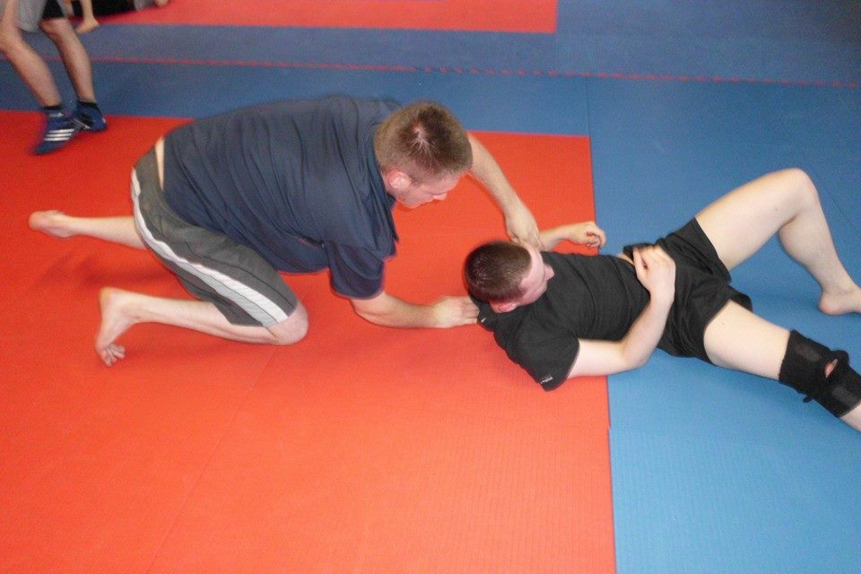 Zwei K&auml;mpfer trainieren in einem Kampfkunststudio auf roten und blauen Matten.