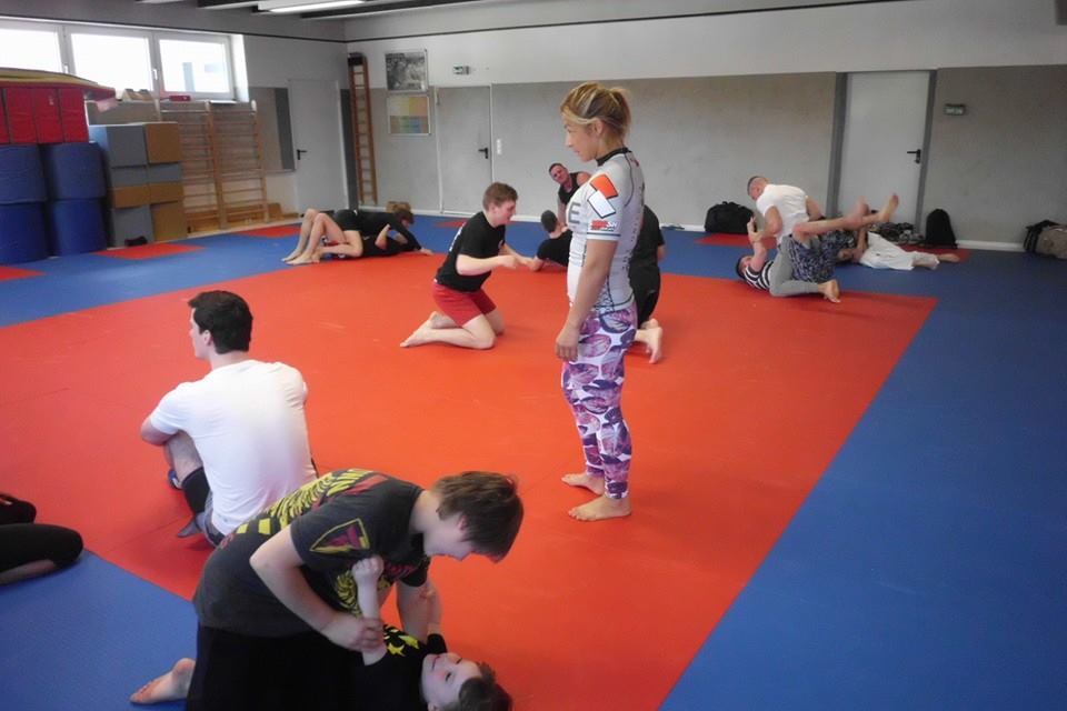 Trainingseinheit in einer Kampfsportschule mit mehreren Teilnehmern auf einer roten Matte.