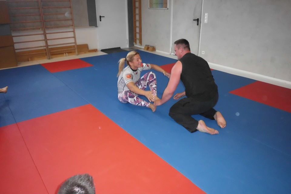 Zwei Personen &uuml;ben auf einer Sportmatte miteinander, die Matte hat rote und blaue Fl&auml;chen.