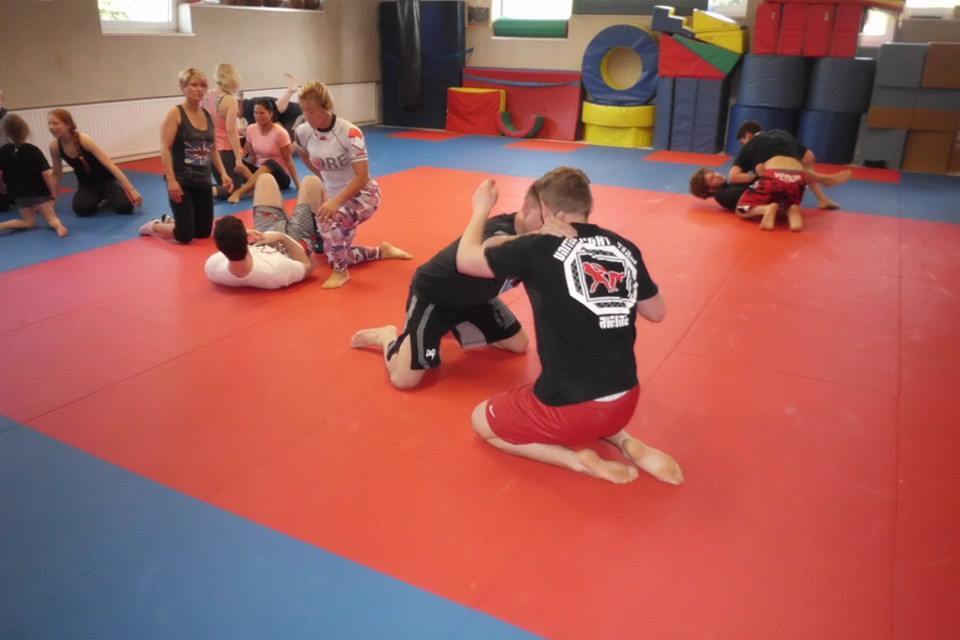 Gruppentraining auf einer Matte: Menschen &uuml;ben verschiedenen Bodenkampf-Techniken in einem Trainingsraum.