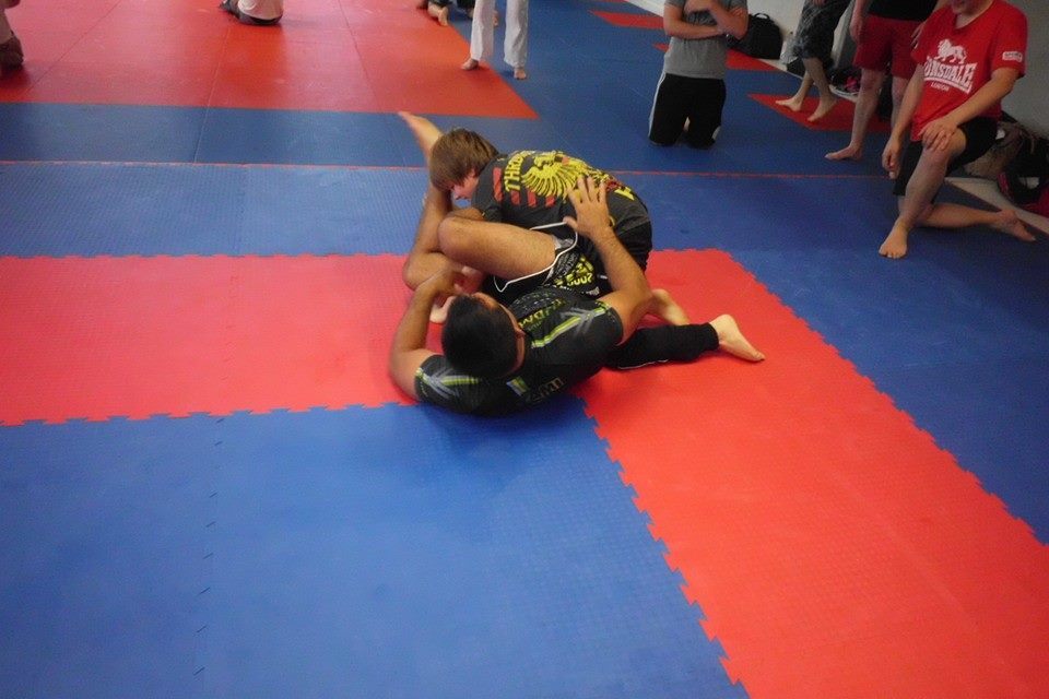 Zwei Sportler zeigen einen Wettkampf auf einer blauen und roten Mattenfl&auml;che im Martial-Arts-Training.